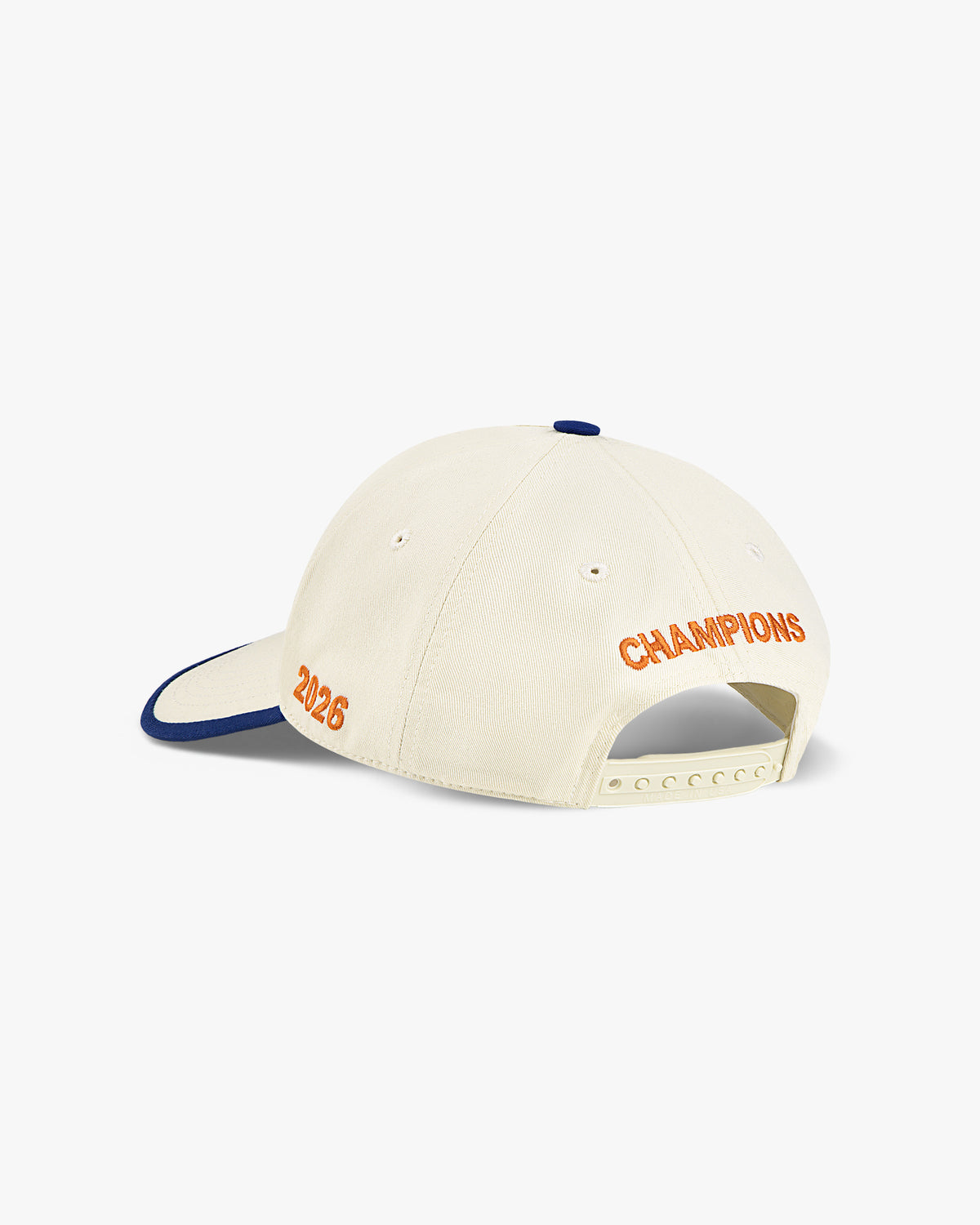 Back three-quarter view of the cream Champions hat with orange 2026 and CHAMPIONS embroidery and royal blue trim