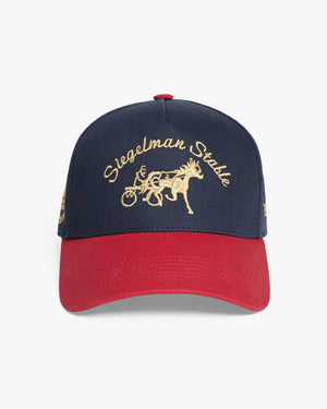 Front view of a navy cap with red visor and gold Siegelman Stable script and horse and sulky embroidery