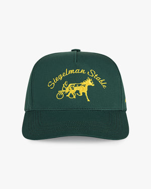 A dark green baseball cap with yellow embroidered text reading 'Siegelman Stable' and a yellow horse-drawn carriage graphic on the front, shown against a light gray background.