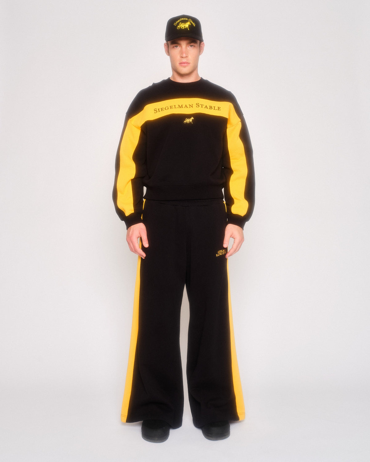 Male model wearing the black retro sweatpants with yellow stripes and the matching retro crewneck