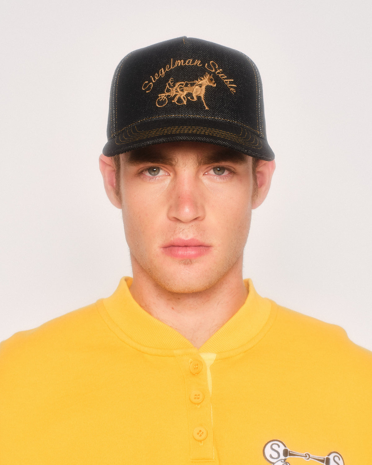 Male model wearing the black contrast denim Siegelman Stable hat with a yellow henley sweatshirt