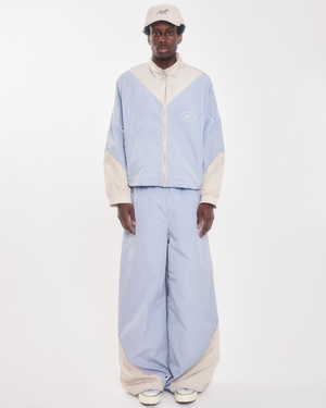 Model wearing the celestial blue and beige retro track pant with a matching track jacket and cream cap