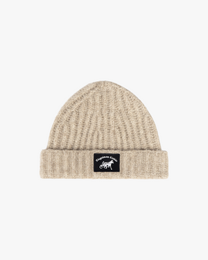Front view of an oatmeal ribbed knit beanie with black horse and sulky logo patch on the cuff
