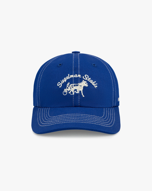 Front view of a royal blue dad hat with white contrast stitching and white Siegelman Stable script and horse logo