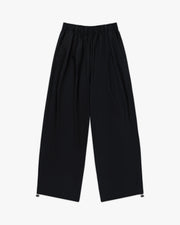 Front view of jet black wide leg parachute pants with elastic waist and toggle hems
