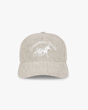 Front view of a beige linen hat with white Siegelman Stable script and horse and sulky embroidery